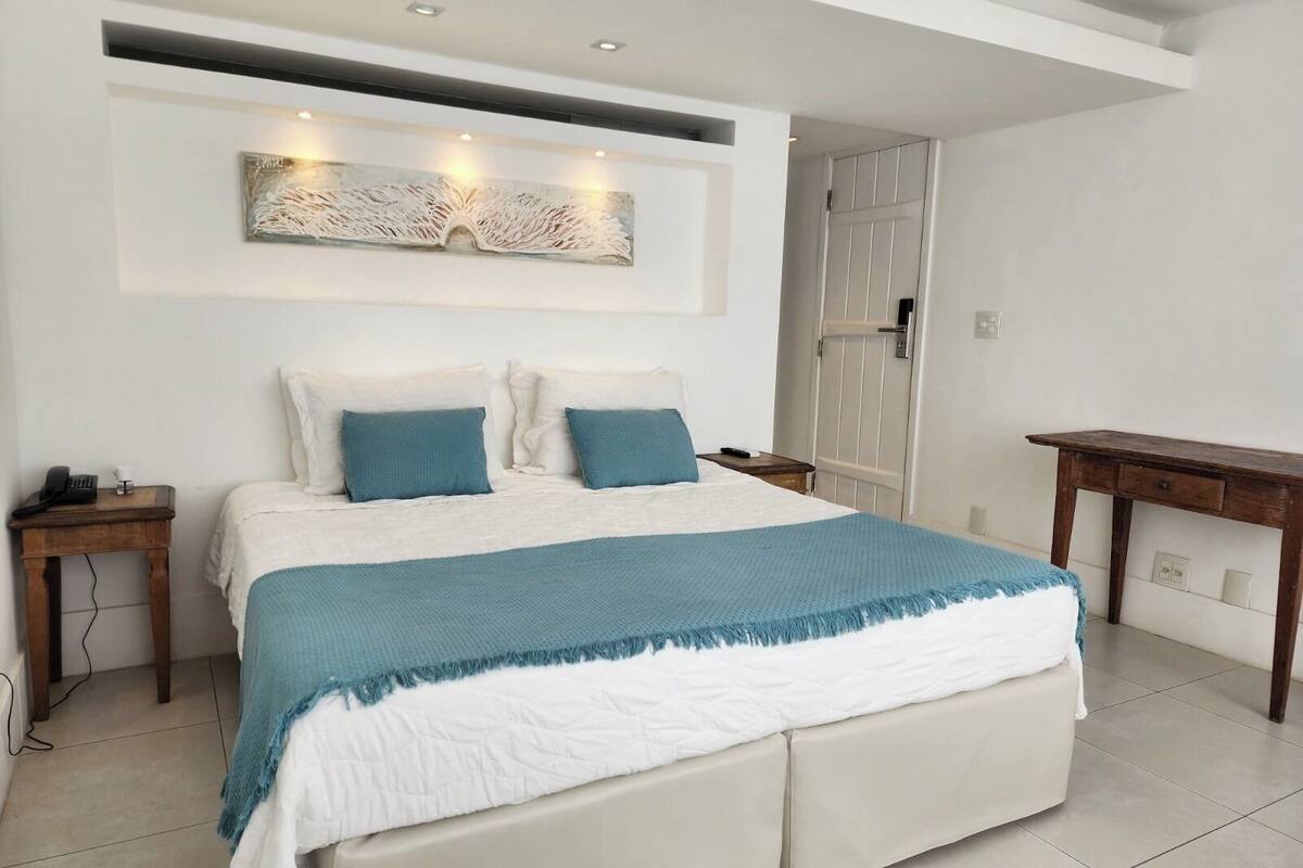 A modern bedroom with a large bed, two bedside tables, a wall-mounted artwork, and a door with a handle.