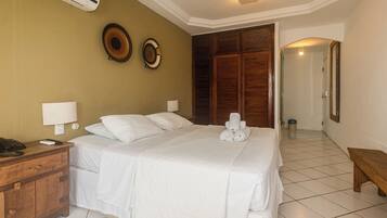 A hotel room with a large bed, a wooden nightstand with a phone, two wall-mounted lamps, and a wooden wardrobe.