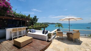 Een terras met buitenmeubilair, een bar en uitzicht op zee.