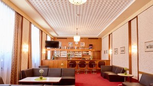 Un hall d’hôtel doté de sièges en cuir, d’un bar et d’un téléviseur.