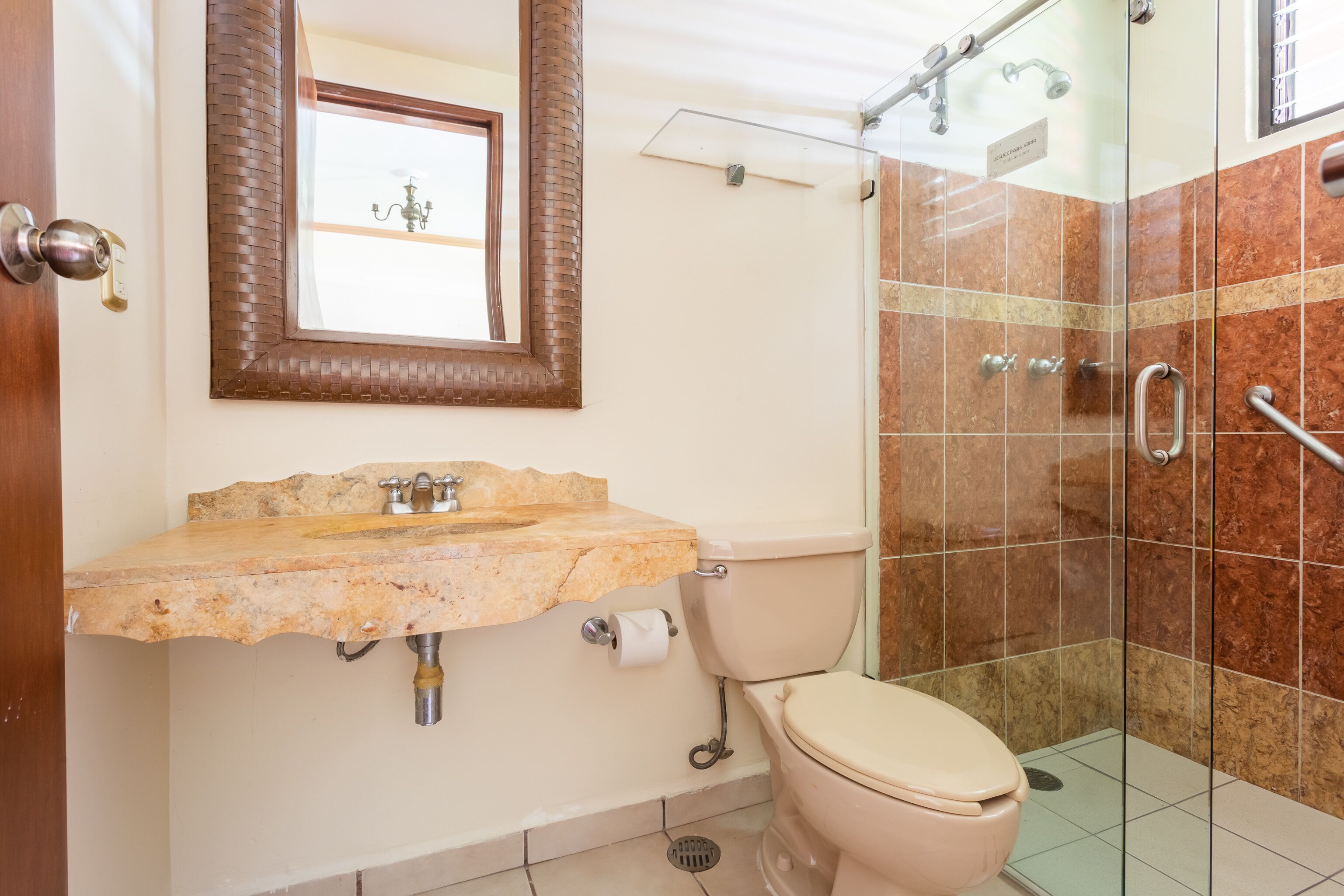 Ein Badezimmer mit Marmorwaschbecken, Toilette und einer Duschkabine aus Glas.