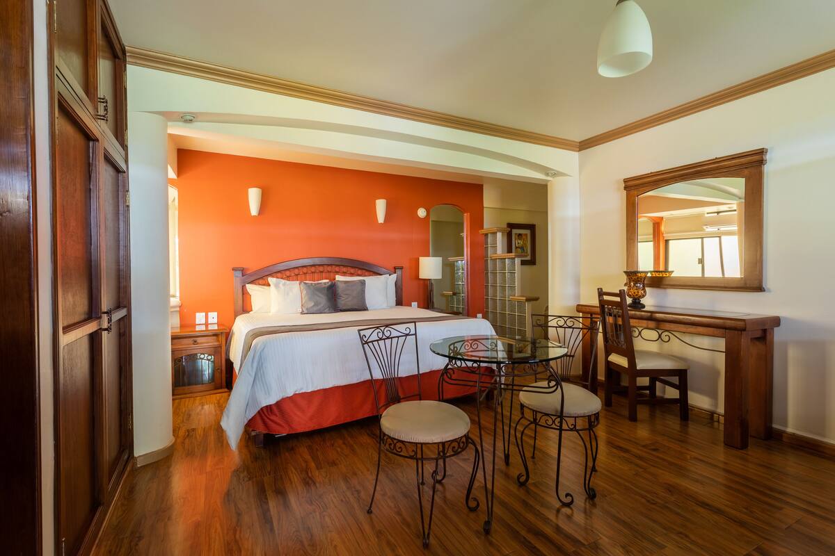 A bedroom with a bed, bedside tables, a desk, and a chair.