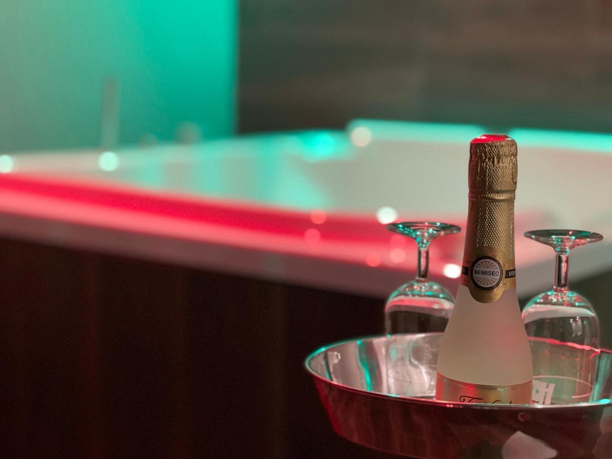 En flaska champagne med guldfolierad etikett, placerad på ett bricka med röd kant.