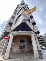 La entrada al Parthotel Arenteiro, con un diseño arquitectónico moderno que destaca una bandera y un cartel de 'No Entry'.