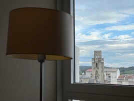 Vista desde una ventana a una torre de piedra histórica con un edificio moderno al frente.