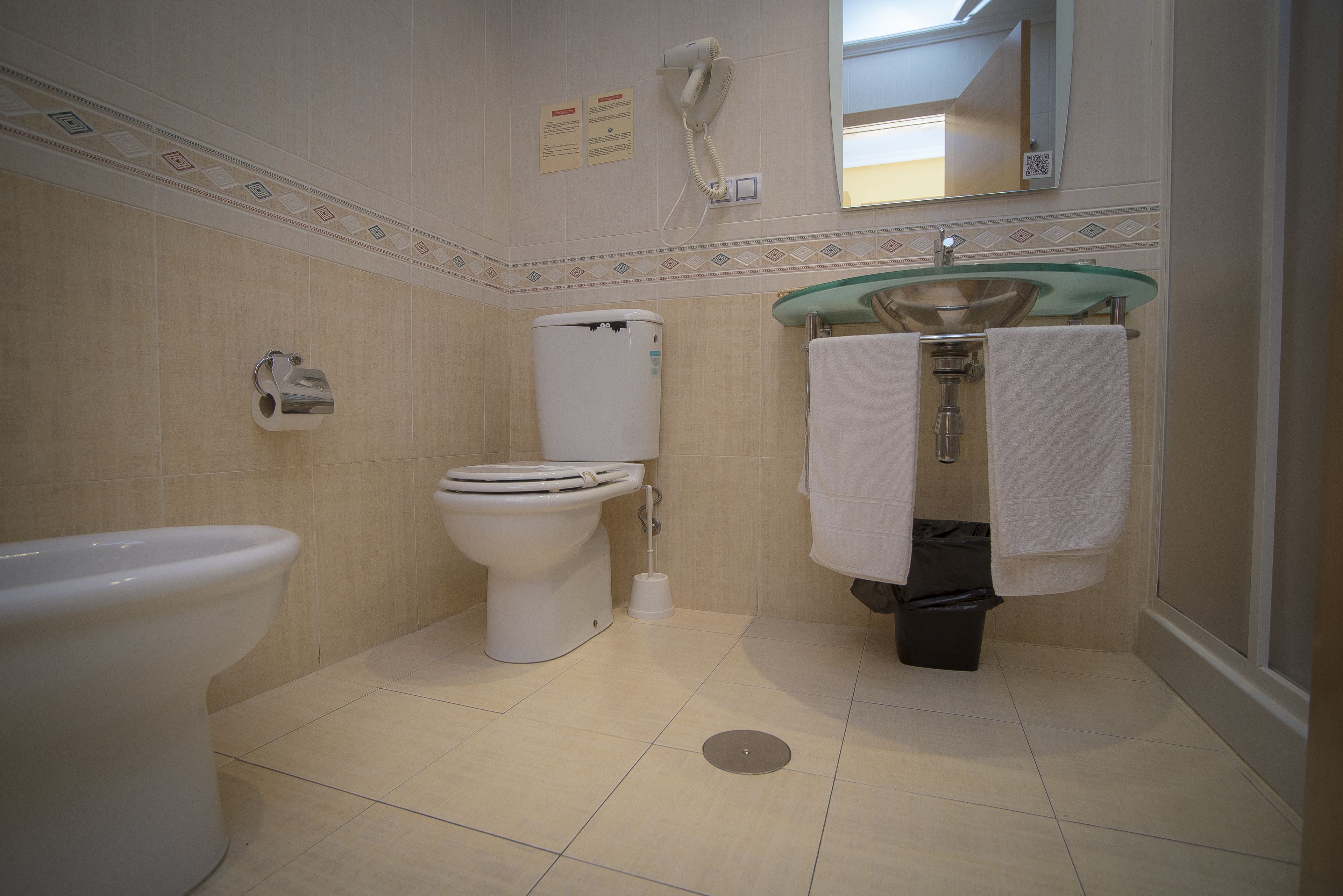A bathroom with a toilet, bidet, sink, and a mirror.