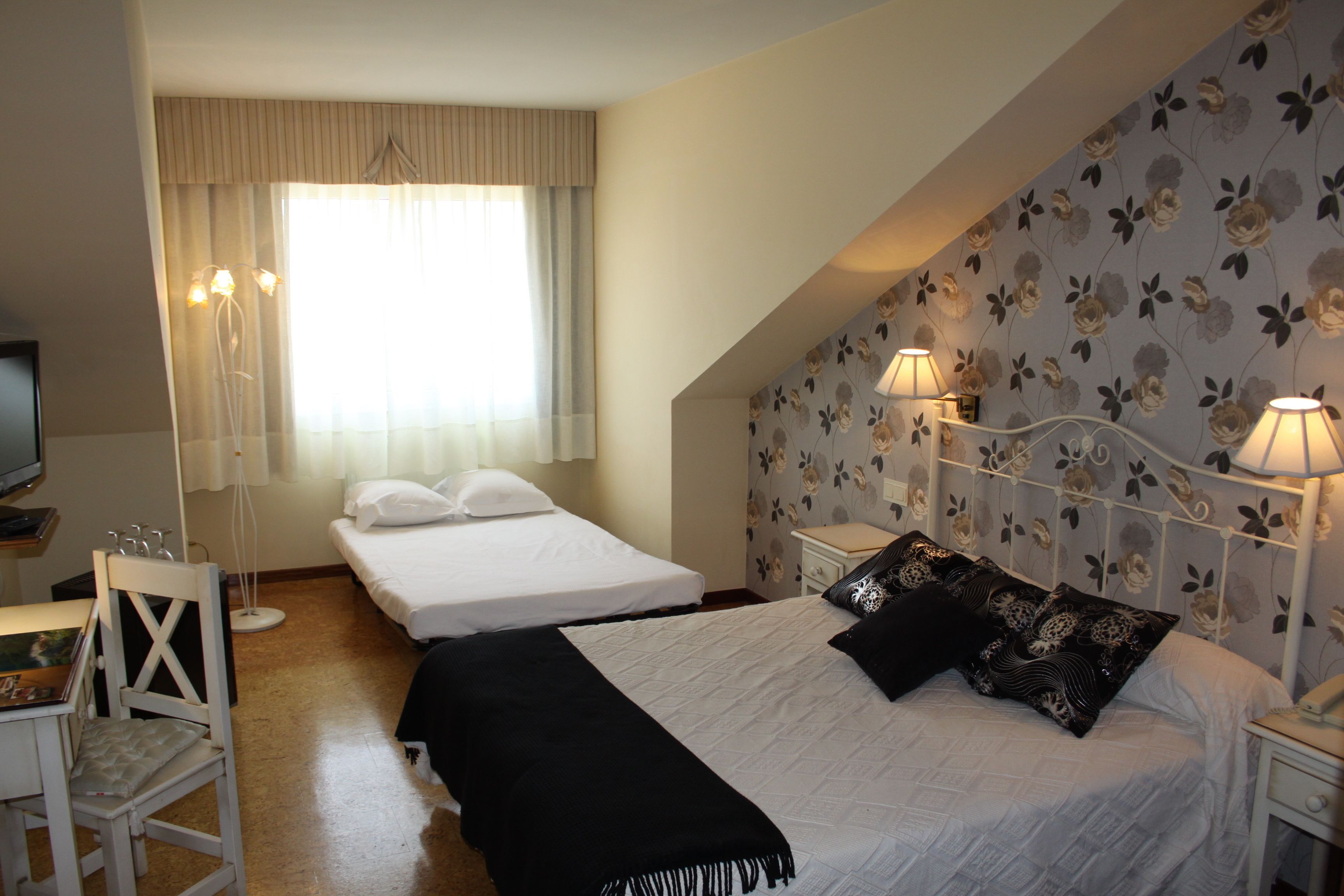 A hotel room with two beds, a television, a desk, and a chair.