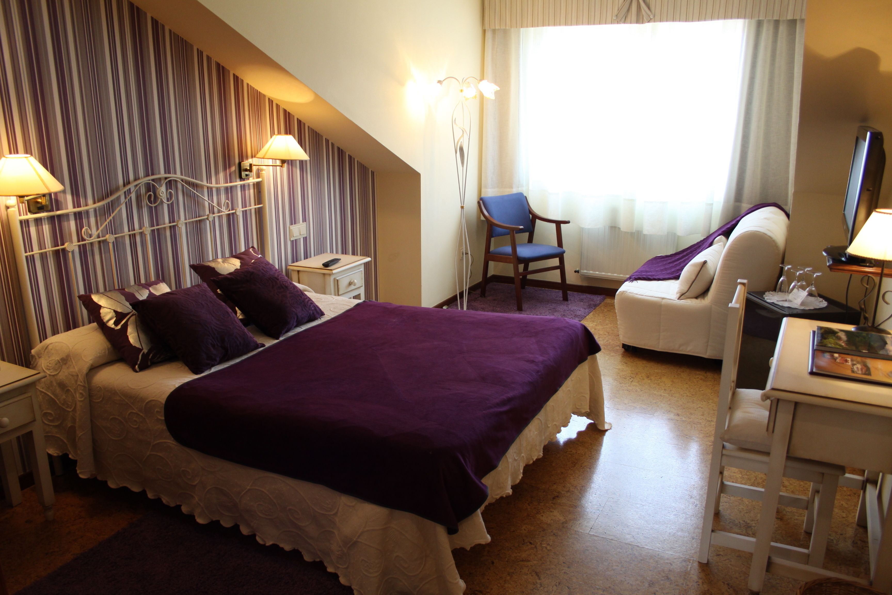 Habitació d'hotel amb llit, escriptori, cadira i televisió.
