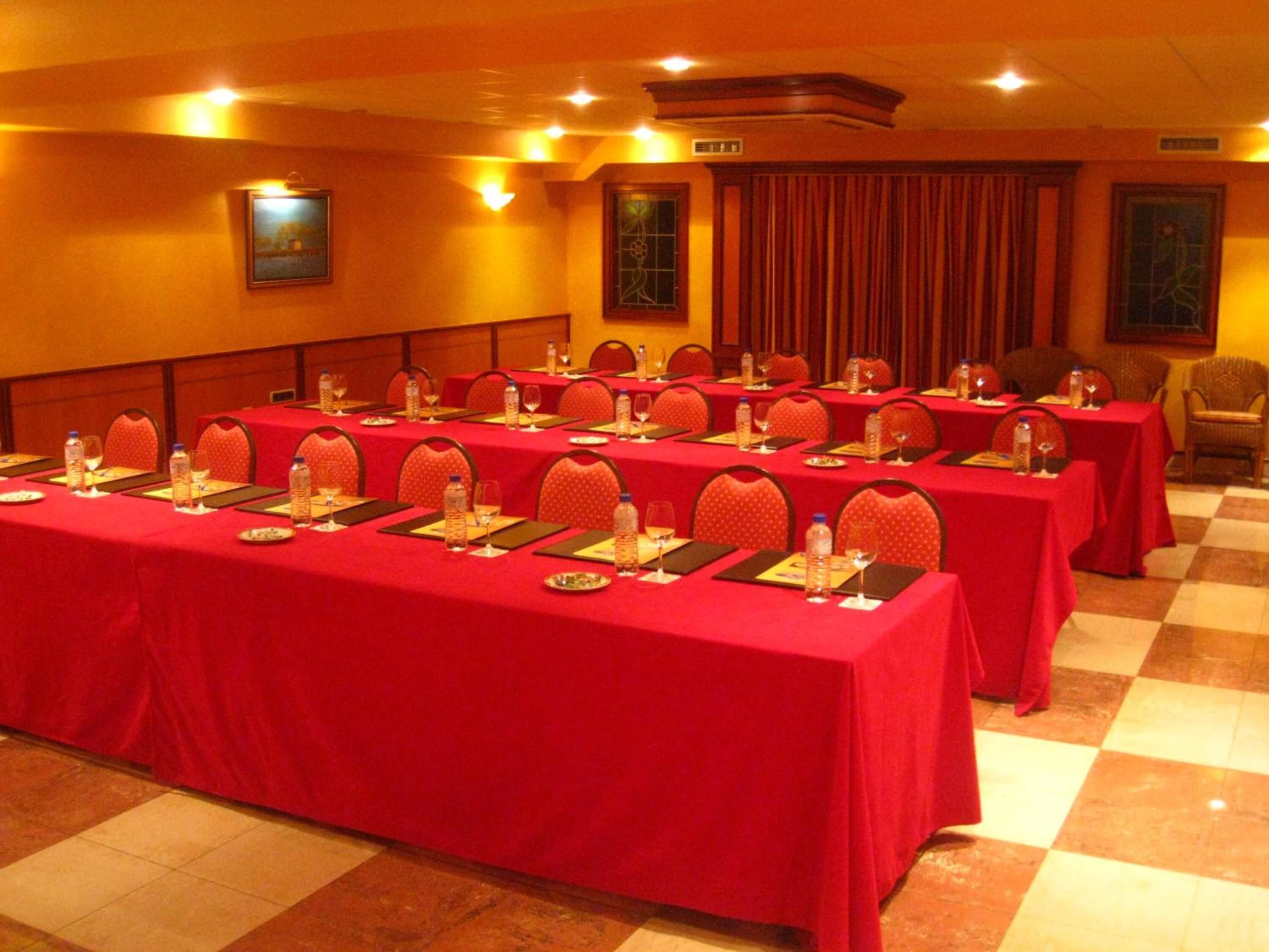 A conference room with multiple tables set up for meetings, equipped with water bottles, glasses, and nameplates.