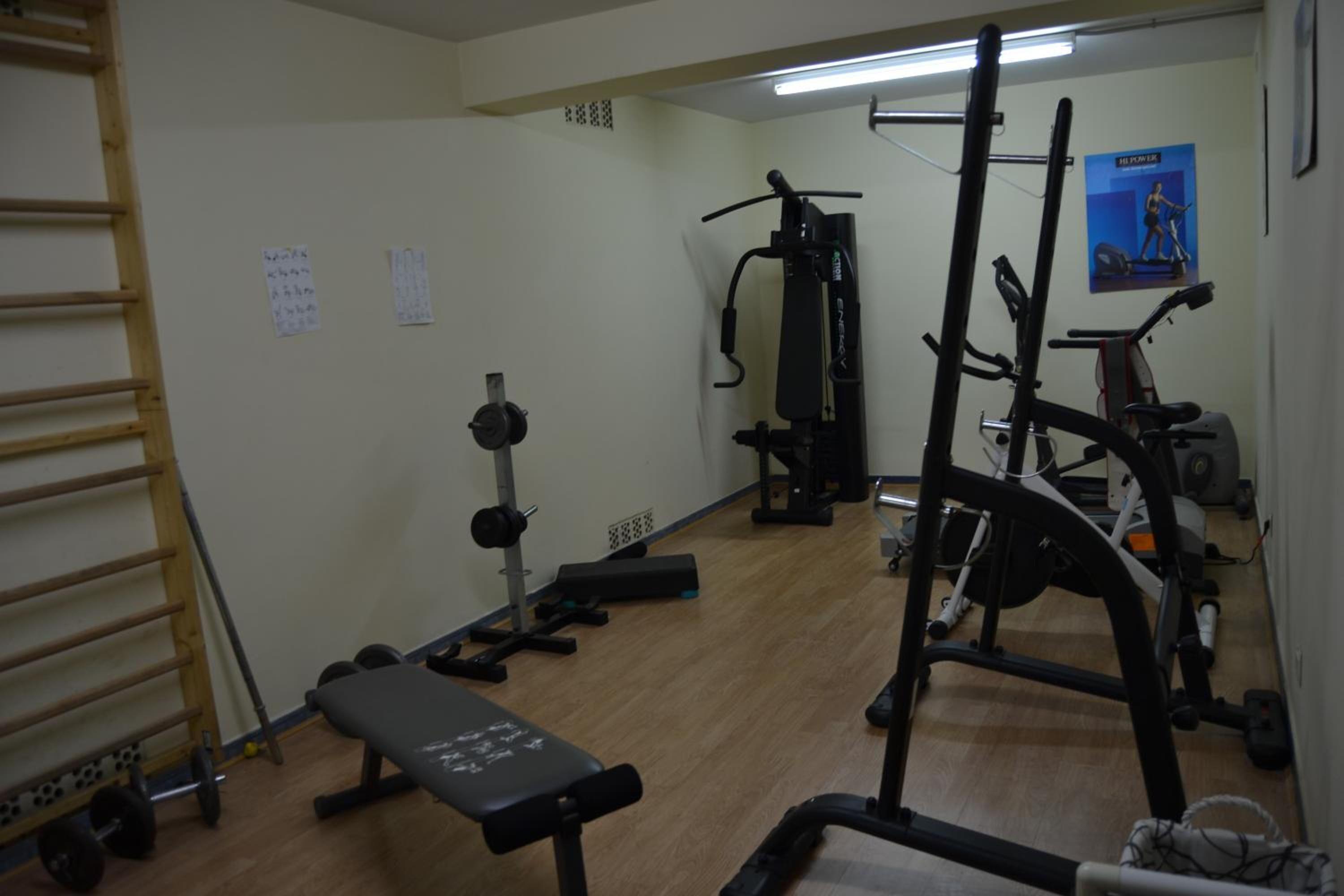 A gym with exercise equipment, a bench, and a pull-up bar.
