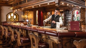 Un bar con taburetes de madera y un camarero sirviendo una bebida.