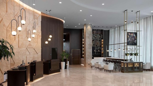 A modern hotel lobby with a reception desk, seating area, and a large window. - Serdika (Sofia)