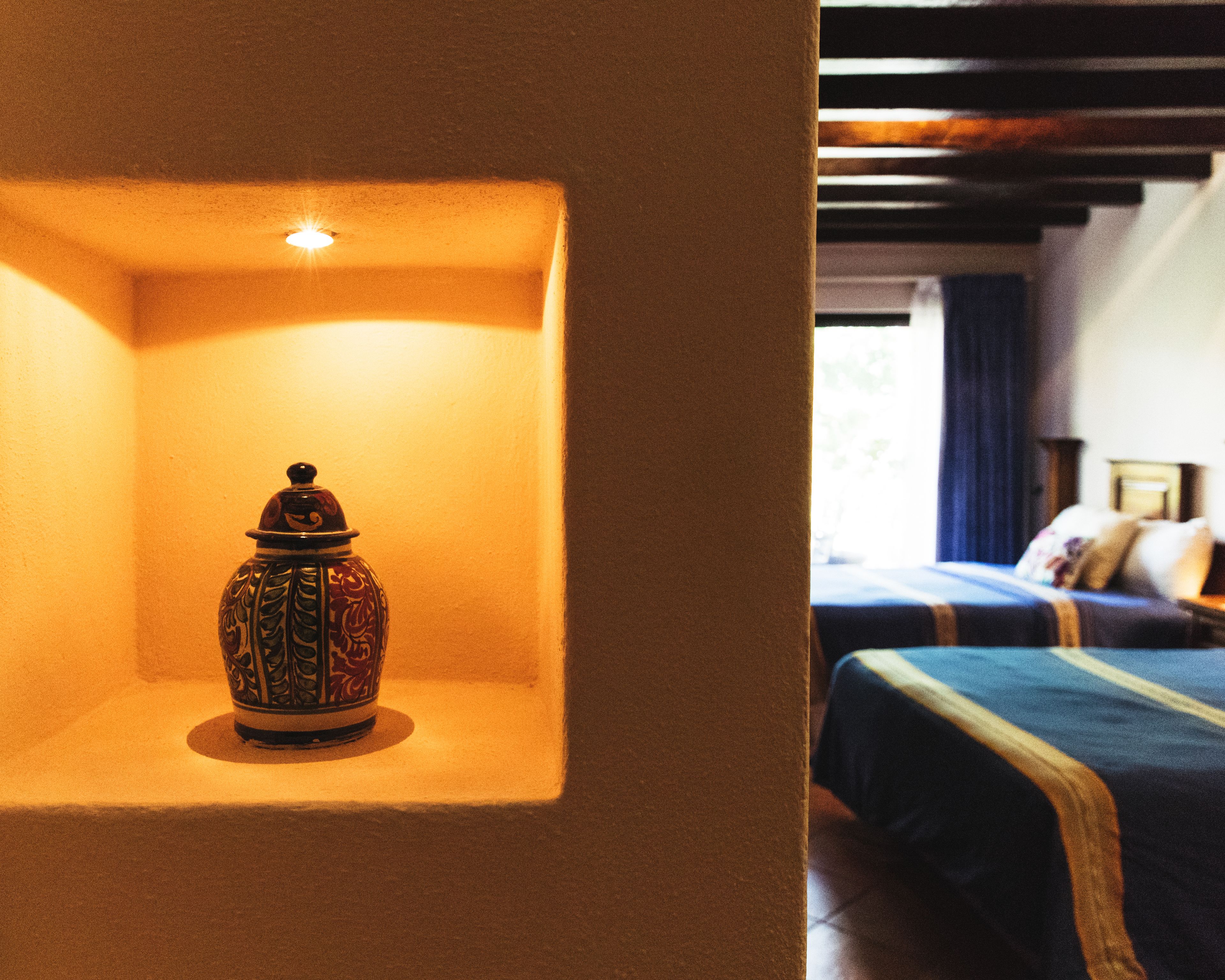 A room with a bed, a nightstand, and a decorative vase on a shelf.