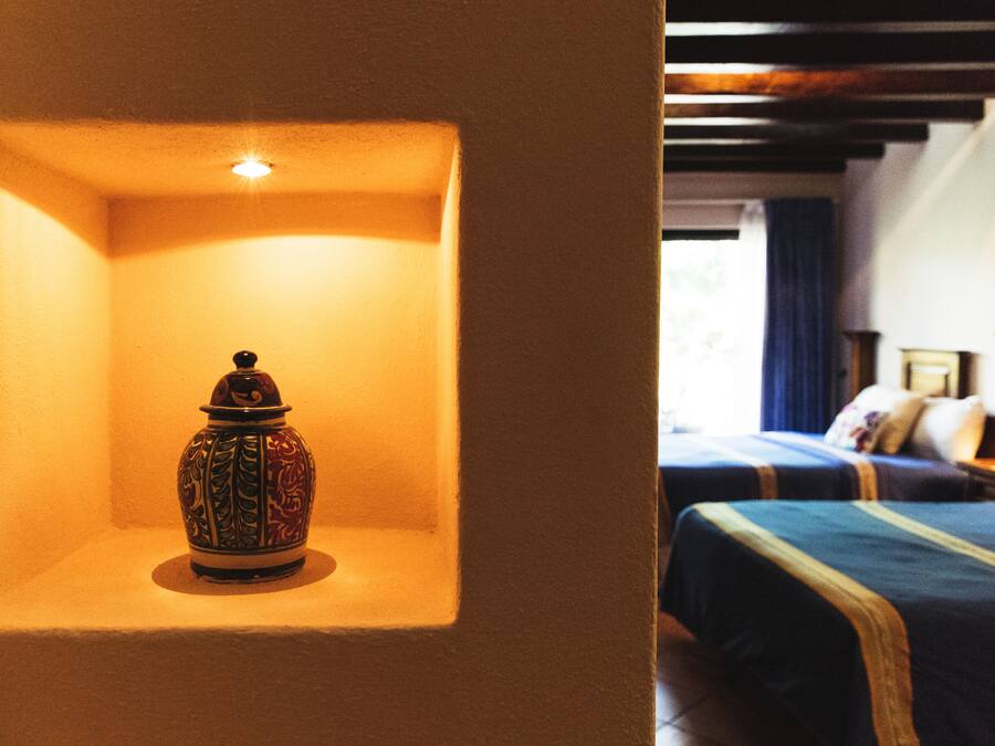 A room with a bed, a nightstand, and a decorative vase on a shelf.