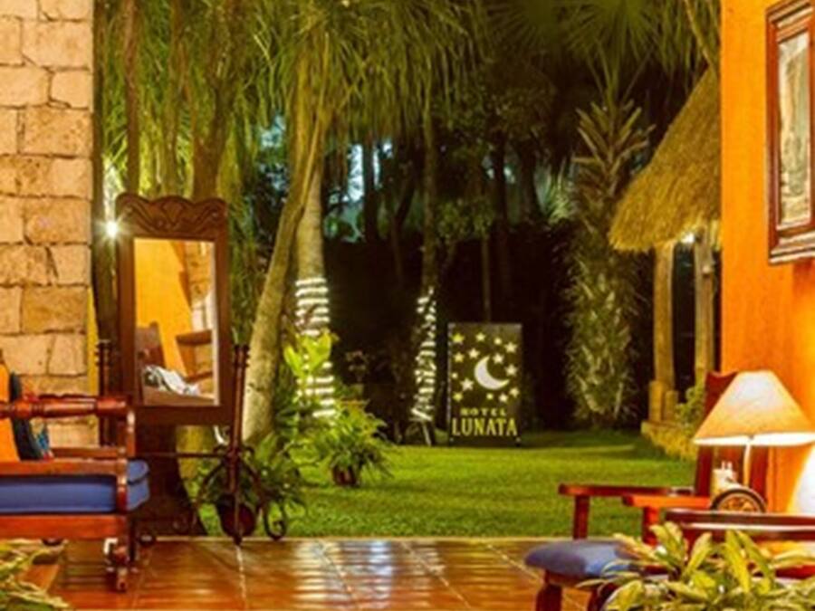 Vestíbulo de hotel con temática tropical, que incluye un arco de piedra, un espejo y un letrero que dice 'Hotel Lunata'.