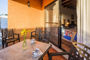 A balcony with a table, chairs, a vase with flowers, and a view of a bedroom with a bed and curtains. - Hotel Lunata - Near Playa del Carmen Main Beach (Playa del Carmen)