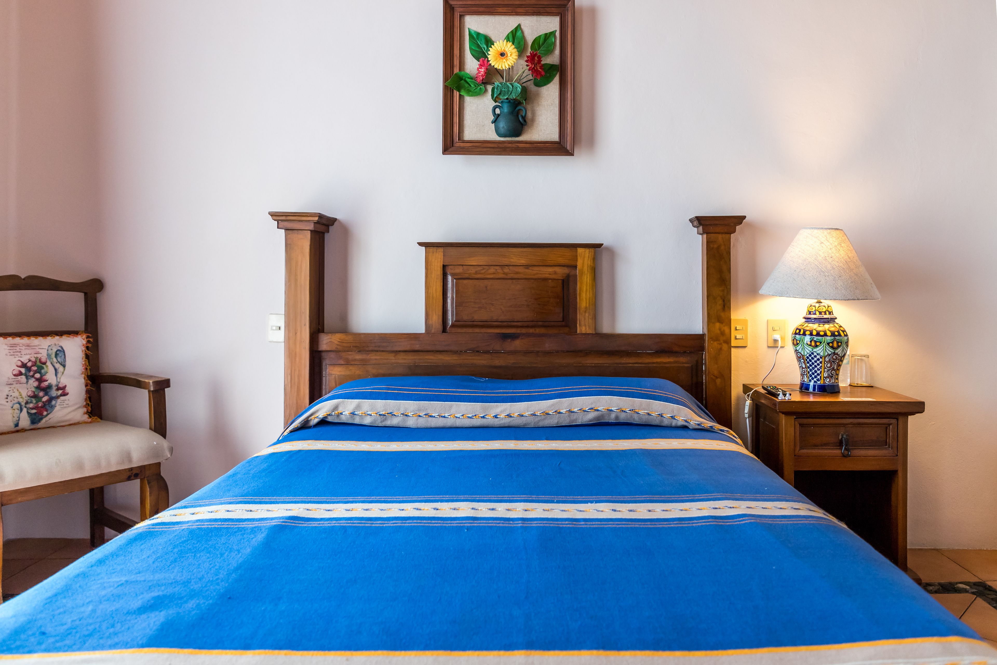 Une chambre à coucher avec un lit, une table de chevet, une lampe et une chaise.