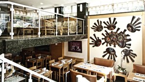 A restaurant with a modern interior, featuring a mezzanine level with seating and a wall decorated with sun-like art pieces. - Park Star Hotel Taksim (Istanbul)