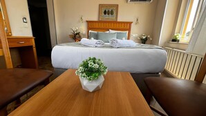 A hotel room with a bed, a wooden headboard, a desk, and a table with a vase of flowers. - Park Star Hotel Taksim (Istanbul)