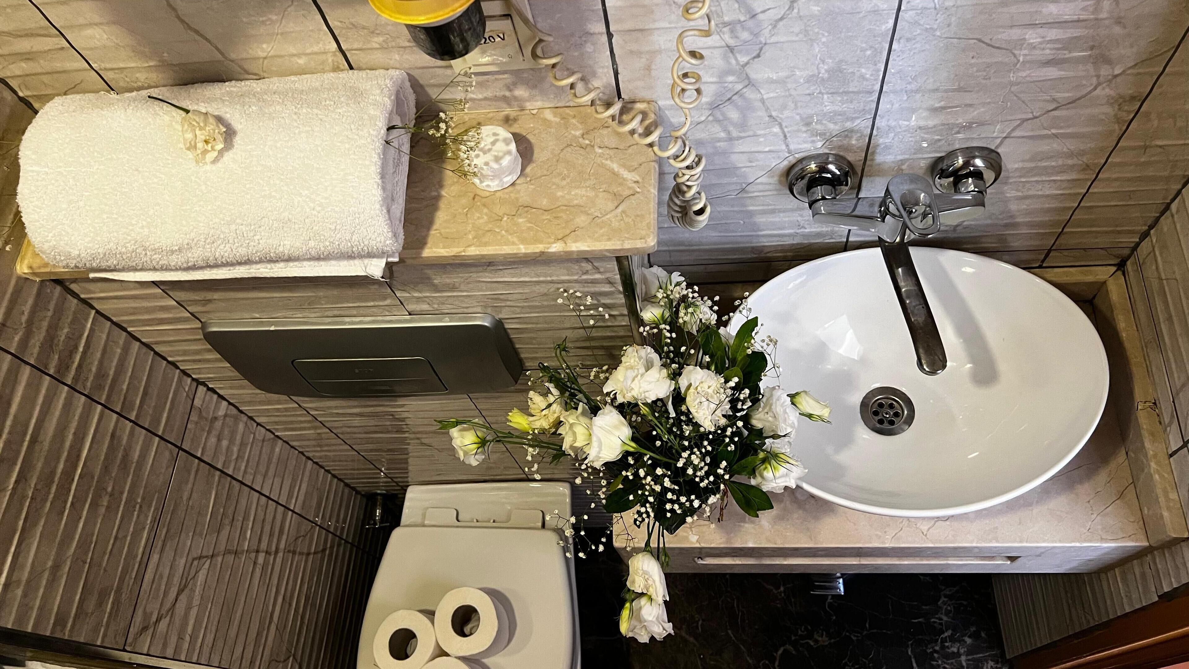 A bathroom with a white sink, a towel, and a toilet.