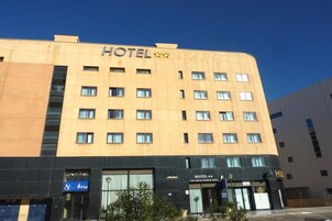 Un edificio de hotel con varios pisos, un letrero que indica que es un hotel y un cartel más pequeño con el nombre del hotel 'VILA-REAL MARINA AZUL'.