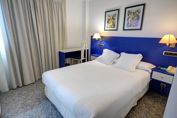 A hotel room with a large bed, two bedside lamps, a desk, and a chair. - Villareal Marina Azul Hotel (Villarreal)