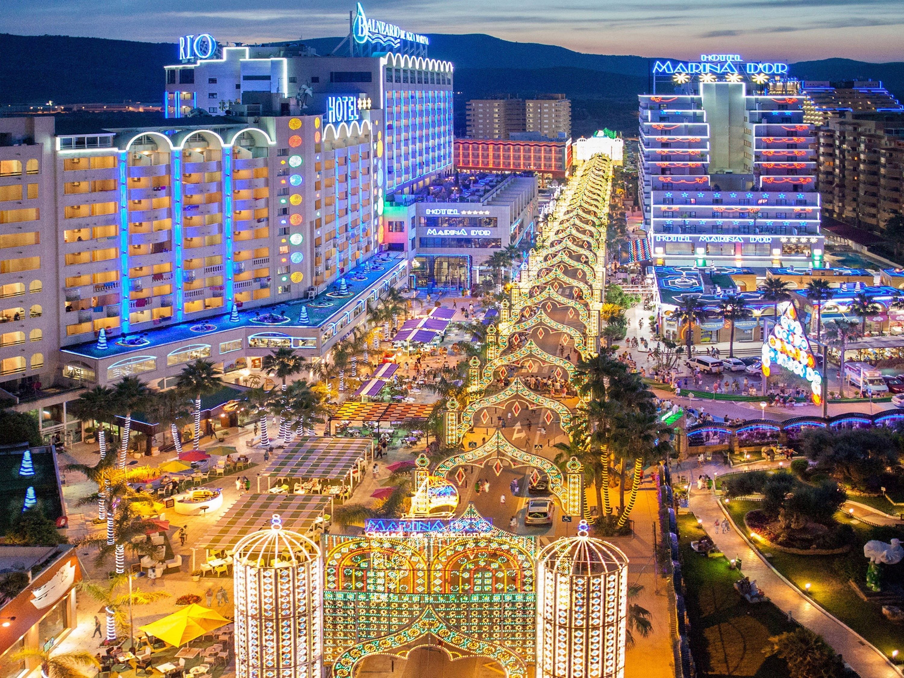 A hotel complex with multiple buildings, including a prominent hotel with balconies and a rooftop area.