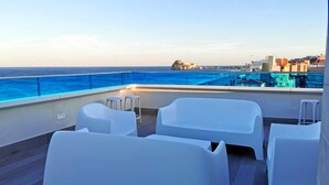 A rooftop terrace with white plastic chairs and a pool. - Hotel Acuazul (Peniscola)