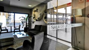 A reading room with modern furniture, a large window, and a view of the outside. - Hotel Acuazul (Peniscola)