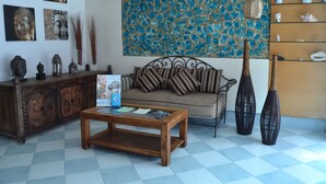A living room with a sofa, coffee table, decorative items, and a stone wall painting. - Aguas Salinas (San Pedro del Pinatar)