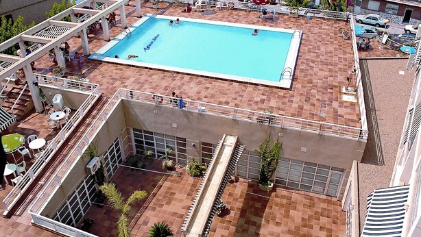 A rooftop pool with a view of the sea, surrounded by buildings and palm trees. - Aguas Salinas (San Pedro del Pinatar)