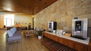 A modern lobby with a stone wall, a sofa, a coffee station, and a seating area.