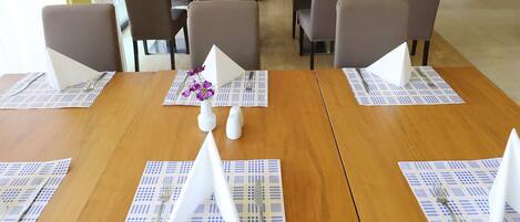 Comedor con mesas de madera, sillas grises y luces de techo azules.
