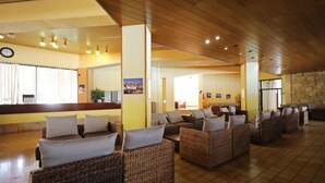 A spacious lobby with wicker furniture, a reception desk, and a clock on the wall.