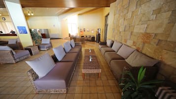 Un hall amplio con sofás de mimbre, suelo de baldosas y pared de piedra.