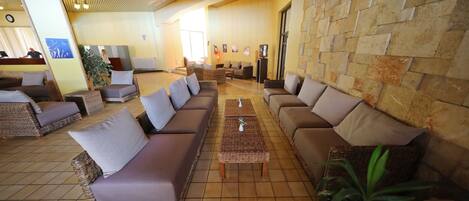 Un hall amplio con sofás de mimbre, suelo de baldosas y pared de piedra.