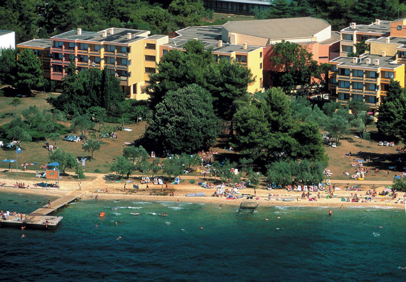 An all-inclusive resort with a sea-side view, featuring multiple buildings and a beach area.