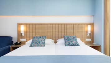 Una cama doble con cabecera de madera, dos mesitas de noche con lámparas y una silla azul.