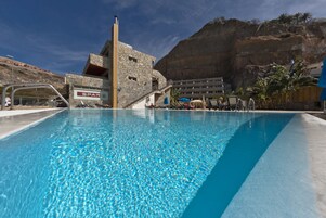 Una piscina al aire libre, sombrillas, tumbonas