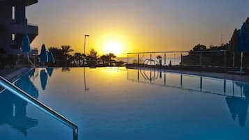 Una piscina al aire libre, sombrillas, tumbonas
