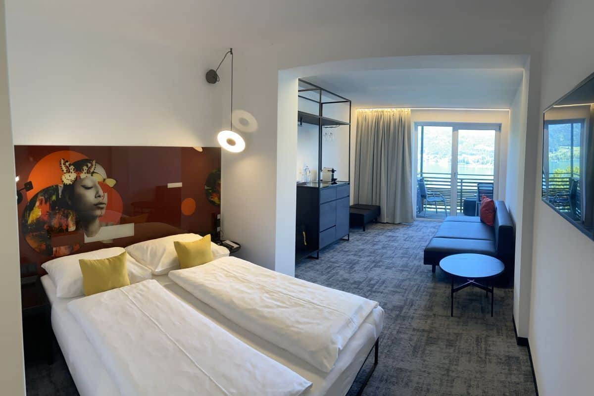 Ein Hotelzimmer mit Bett, Schreibtisch, Sofa und einem Balkon mit Blick.