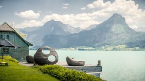 A lakeside wooden structure with outdoor seating and a view of mountains. - Scalaria Sunset Wing (Sankt Wolfgang im Salzkammergut)