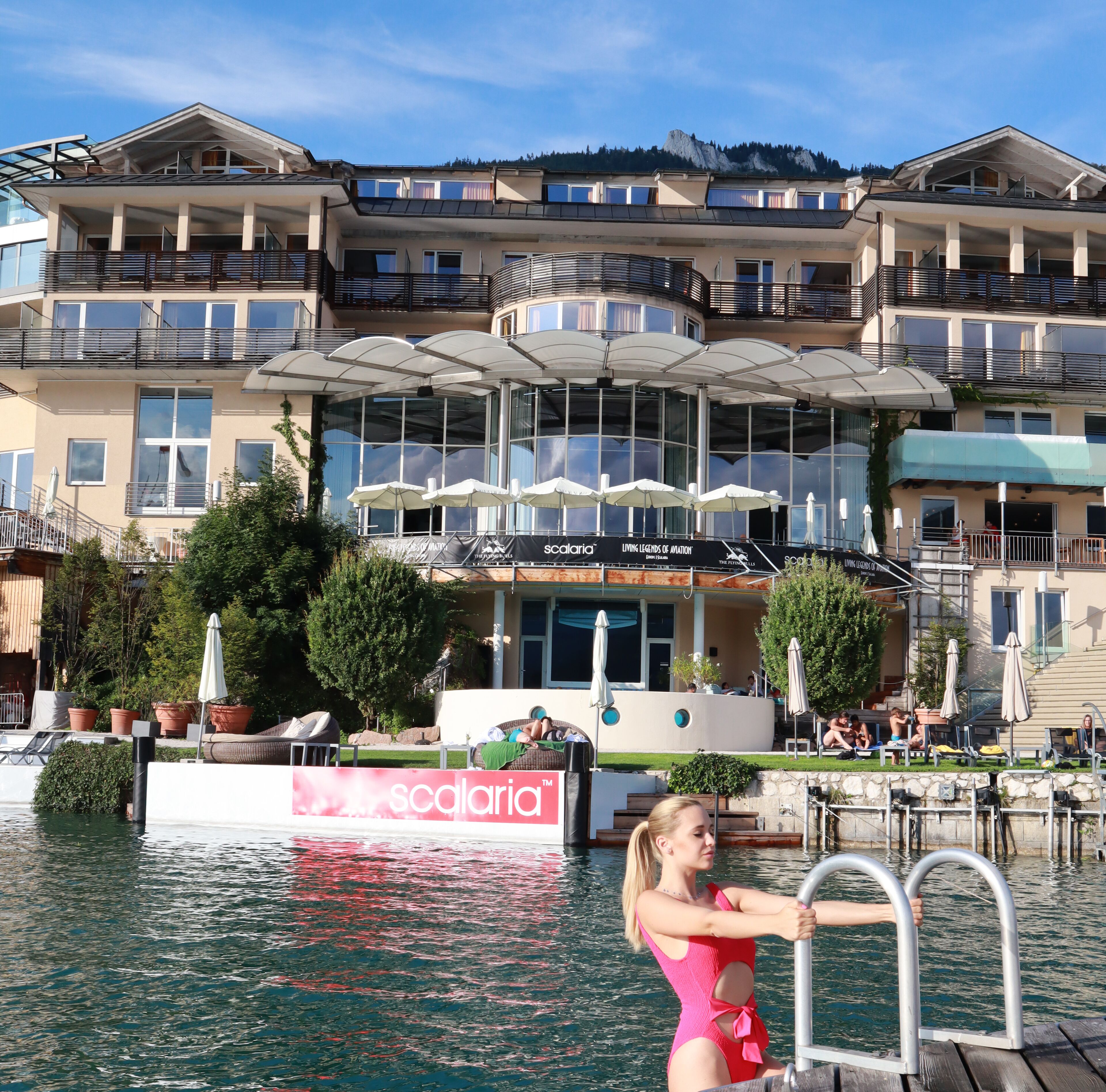 A hotel with a pool area, outdoor seating, and a view of a mountain.