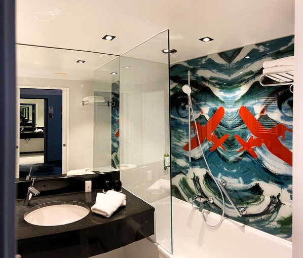 A modern bathroom with a glass shower enclosure, a black countertop sink, and a large mirror.