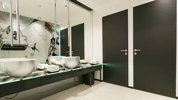 Un baño moderno con dos lavamanos grandes, un espejo y dos puertas negras.