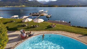 A swimming pool with a view of a lake, a dock with boats, and lounge chairs. - Scalaria Sunset Wing (Sankt Wolfgang im Salzkammergut)