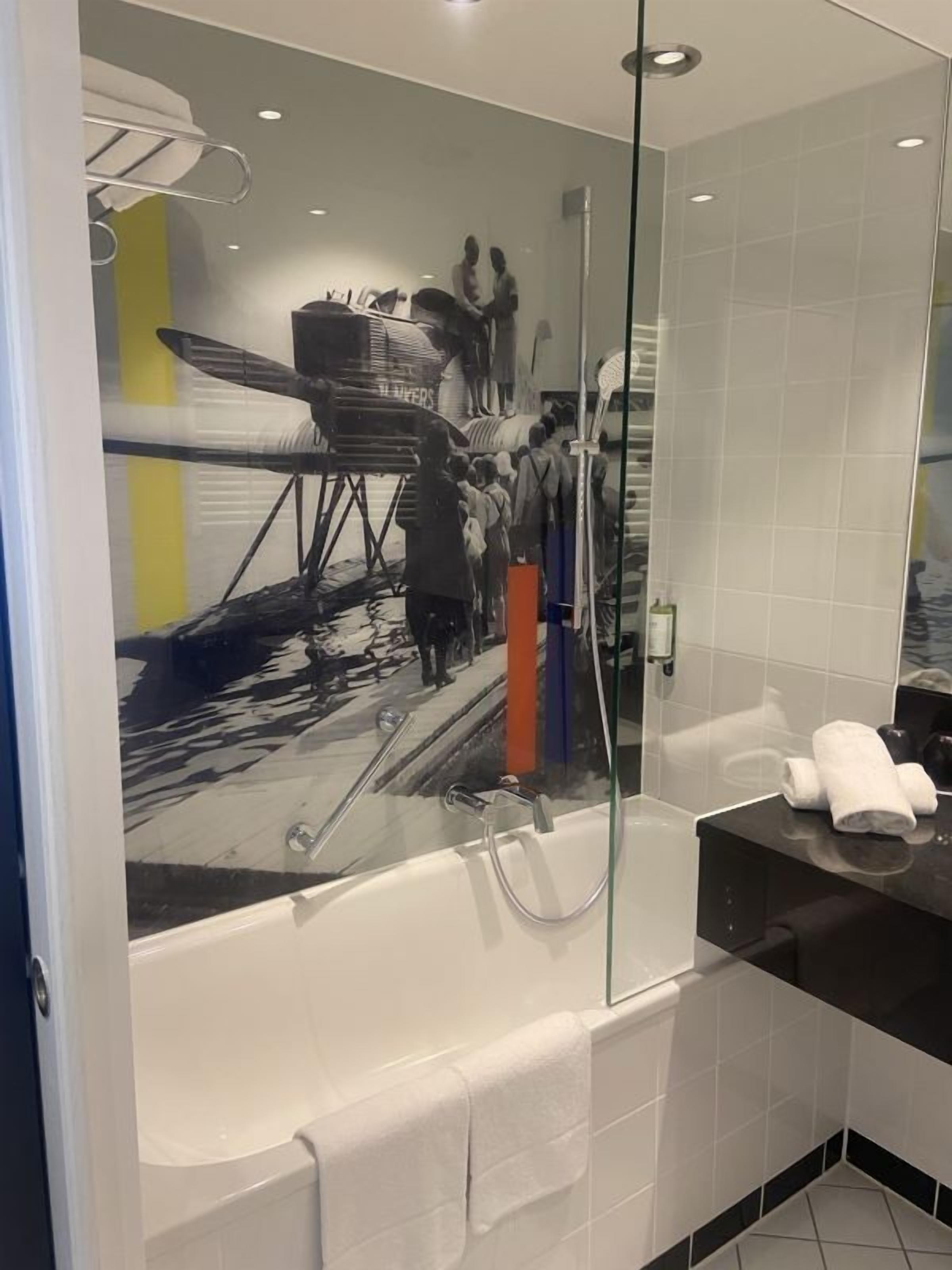 A modern bathroom with a glass shower enclosure, a white bathtub, and a black countertop with a towel.