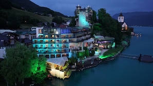 A lakeside hotel with multiple buildings, a tower, and a church. - Scalaria Sunset Wing (Sankt Wolfgang im Salzkammergut)