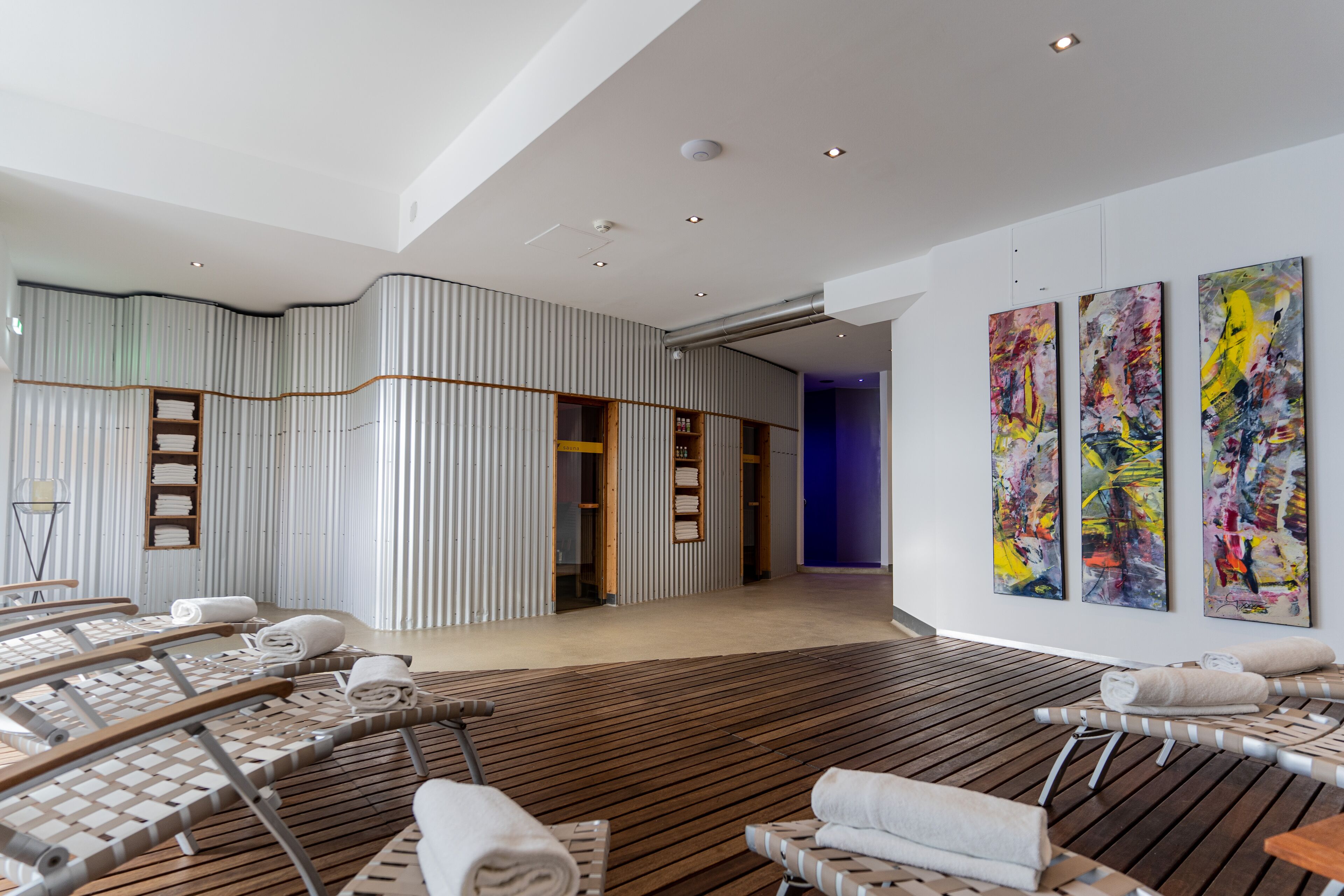 A modern spa with wooden loungers, a striped wall, and abstract art.