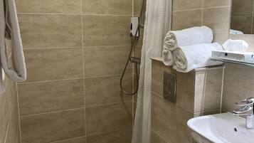A bathroom with a shower, toilet, sink, and towel rack.